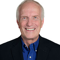 A headshot photo of Dave Jewitt wearing a dark sportsjacket and a dark blue button up shirt.