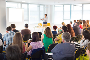 A Your One Degree workshop with a coach sharing information in front of a group of participants.